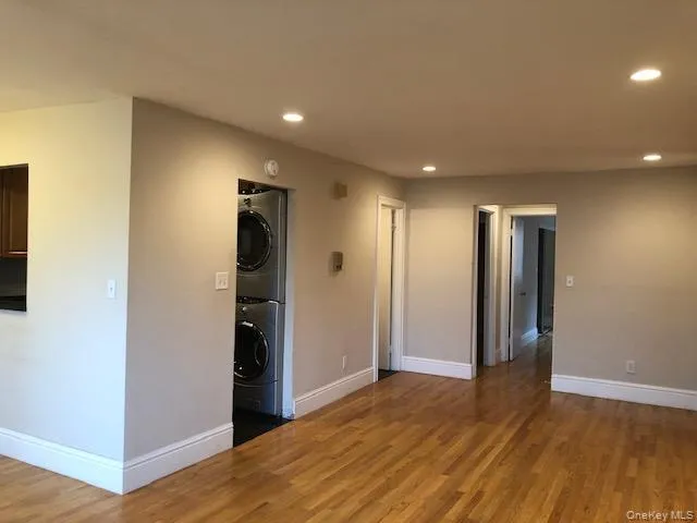 Spare room featuring recessed lighting, wood finished floors, and stacked washer and clothes dryer Spare room featuring recessed lighting, wood finished floors, and stacked washer and clothes dryer