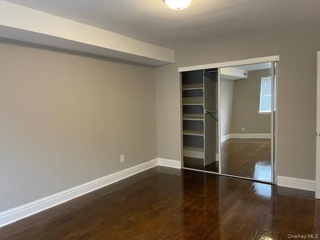 Unfurnished bedroom featuring dark wood-style flooring and a closet Unfurnished bedroom featuring dark wood-style flooring and a closet