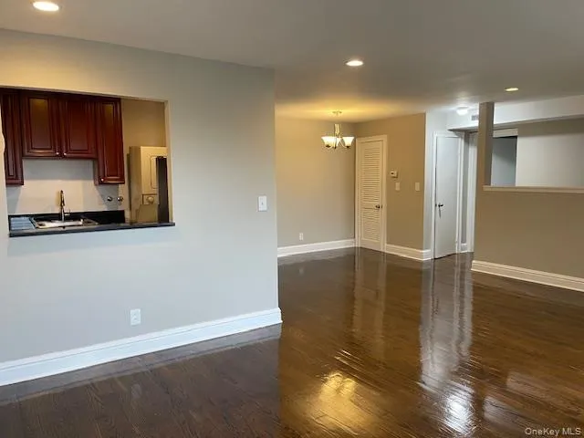 Unfurnished living room featuring recessed lighting, dark wood-style floors, and a chandelier Unfurnished living room featuring recessed lighting, dark wood-style floors, and a chandelier