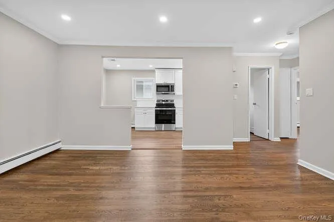 Unfurnished living room featuring recessed lighting, ornamental molding, and dark wood-style flooring Unfurnished living room featuring recessed lighting, ornamental molding, and dark wood-style flooring