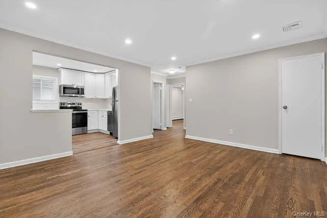 Unfurnished living room with crown molding, dark wood-style flooring, and recessed lighting Unfurnished living room with crown molding, dark wood-style flooring, and recessed lighting