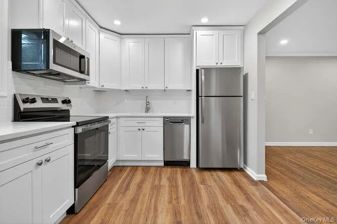 Kitchen featuring appliances with stainless steel finishes, white cabinetry, recessed lighting, and light wood-style floors Kitchen featuring appliances with stainless steel finishes, white cabinetry, recessed lighting, and light wood-style floors