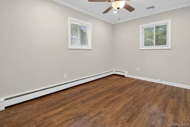 Empty room featuring baseboard heating, ornamental molding, dark wood finished floors, a ceiling fan, and recessed lighting Empty room featuring baseboard heating, ornamental molding, dark wood finished floors, a ceiling fan, and recessed lighting