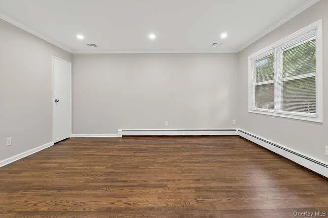 Unfurnished room with crown molding, dark wood-style floors, recessed lighting, and baseboard heating Unfurnished room with crown molding, dark wood-style floors, recessed lighting, and baseboard heating