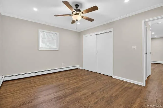 Unfurnished bedroom with crown molding, dark wood-type flooring, a ceiling fan, recessed lighting, and baseboard heating Unfurnished bedroom with crown molding, dark wood-type flooring, a ceiling fan, recessed lighting, and baseboard heating