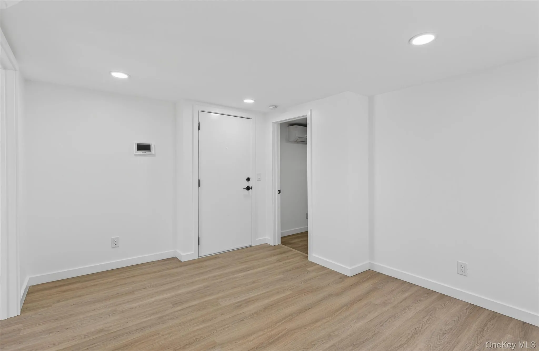 Unfurnished room with light wood finished floors, recessed lighting, and a wall unit AC Unfurnished room with light wood finished floors, recessed lighting, and a wall unit AC