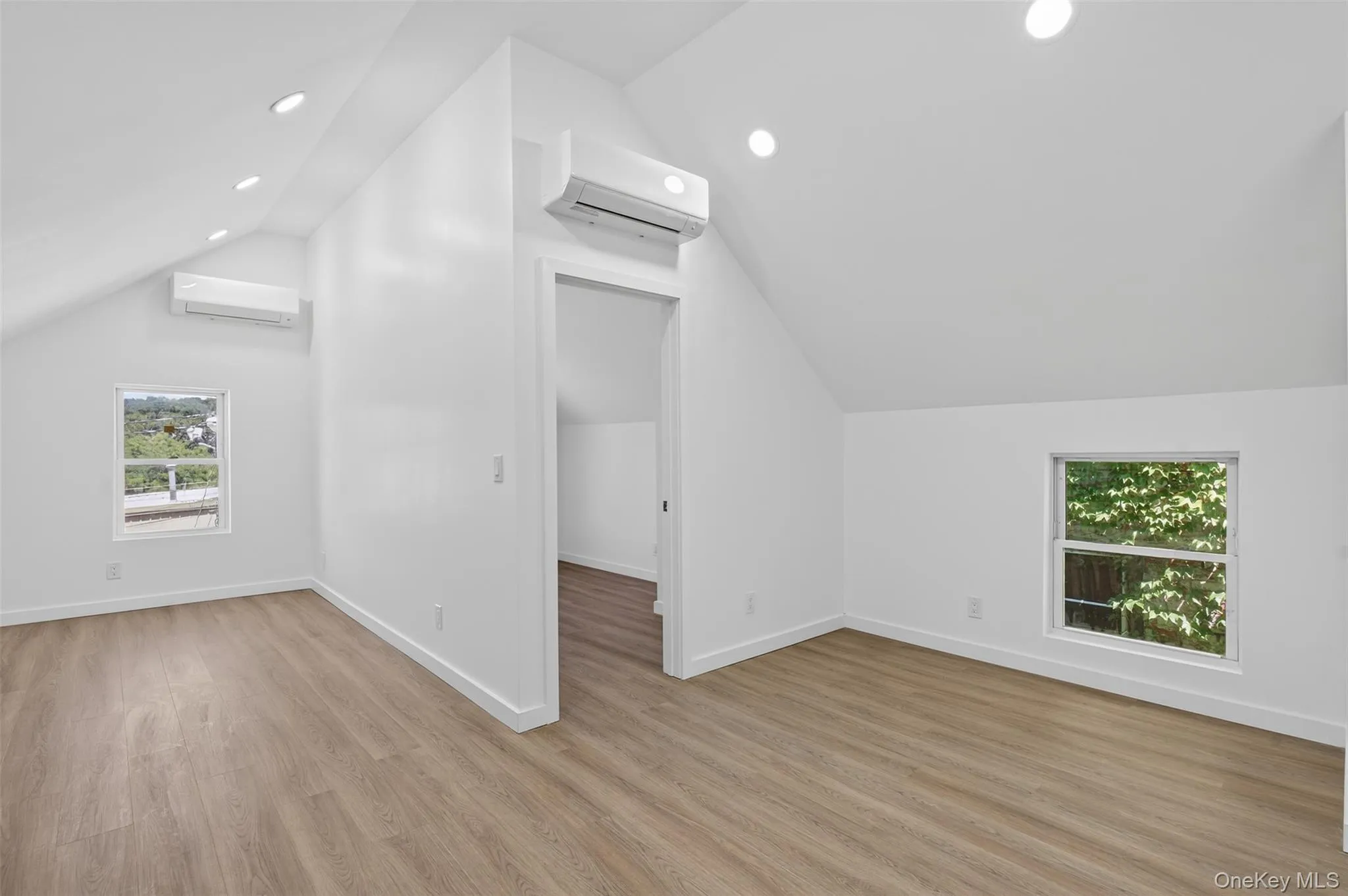 Additional living space featuring light wood finished floors, lofted ceiling, recessed lighting, and a wall mounted air conditioner Additional living space featuring light wood finished floors, lofted ceiling, recessed lighting, and a wall mounted air conditioner