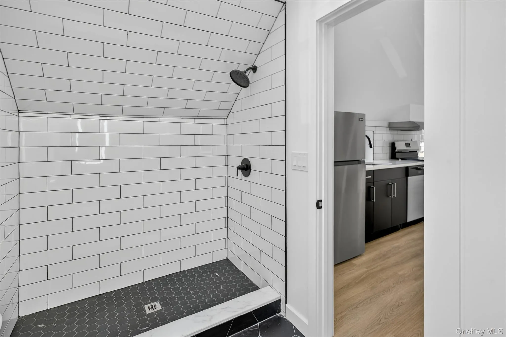 Bathroom featuring a shower stall, vanity, backsplash, and light wood-type flooring Bathroom featuring a shower stall, vanity, backsplash, and light wood-type flooring