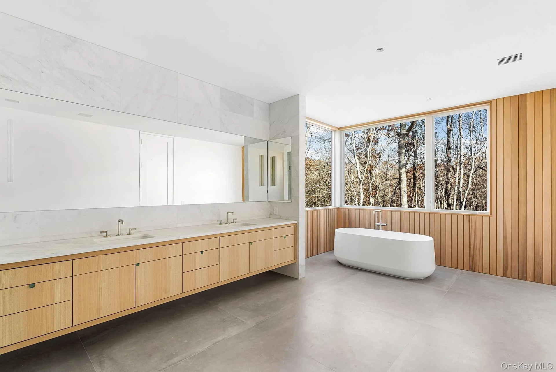 Full bath with a freestanding bath, double vanity, concrete floors, and wood walls Full bath with a freestanding bath, double vanity, concrete floors, and wood walls