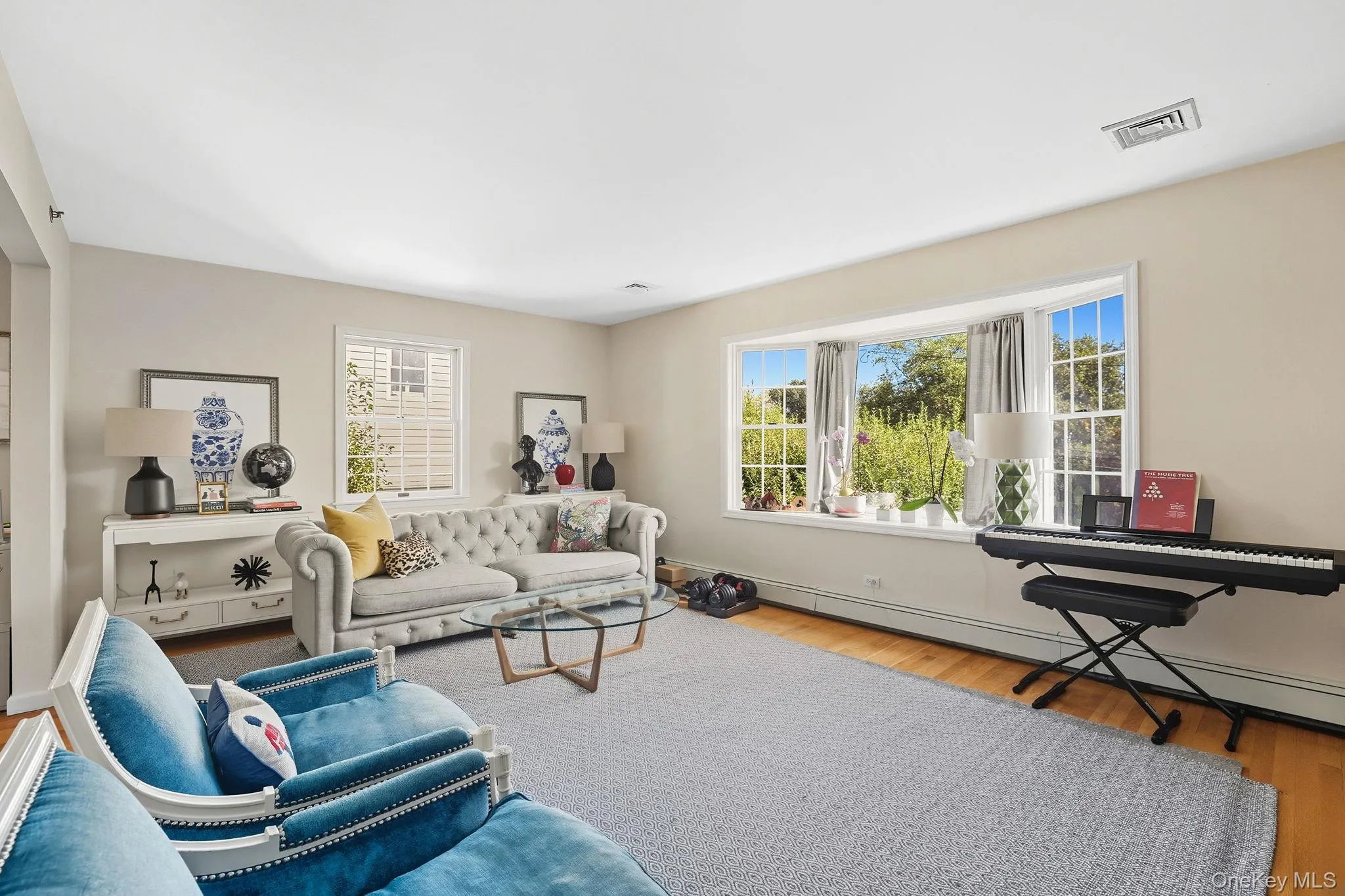 Living room with hardwood floors, bay window, and ample natural light Living room with hardwood floors, bay window, and ample natural light