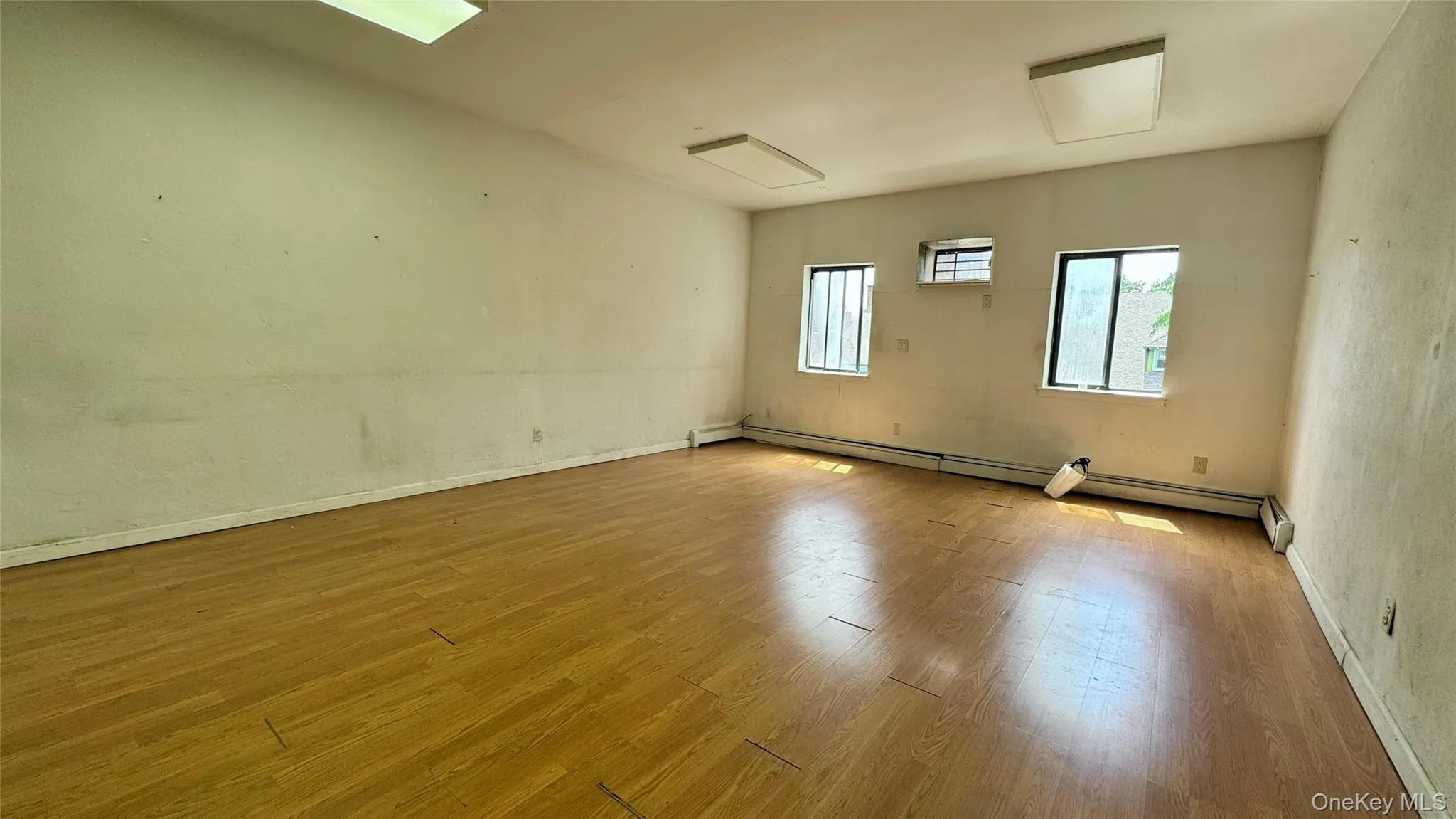 Unfurnished room featuring wood finished floors and baseboard heating Unfurnished room featuring wood finished floors and baseboard heating