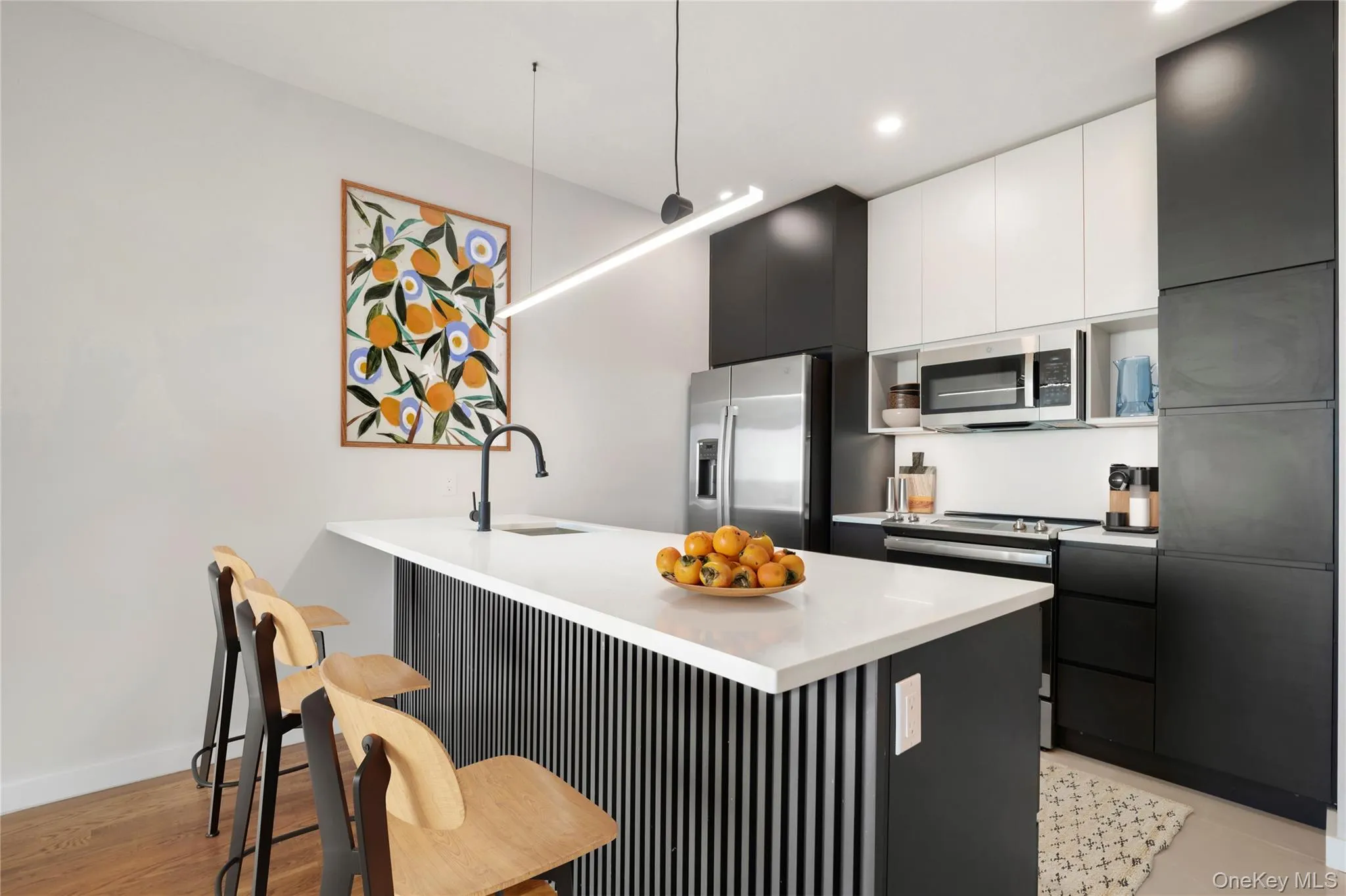 Kitchen featuring appliances with stainless steel finishes, a sink, a kitchen breakfast bar, modern cabinets, and white cabinetry Kitchen featuring appliances with stainless steel finishes, a sink, a kitchen breakfast bar, modern cabinets, and white cabinetry