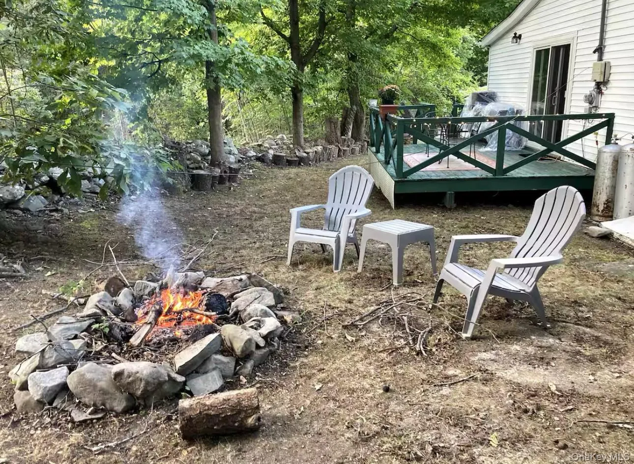 View of yard featuring a wooden deck and an outdoor fire pit View of yard featuring a wooden deck and an outdoor fire pit