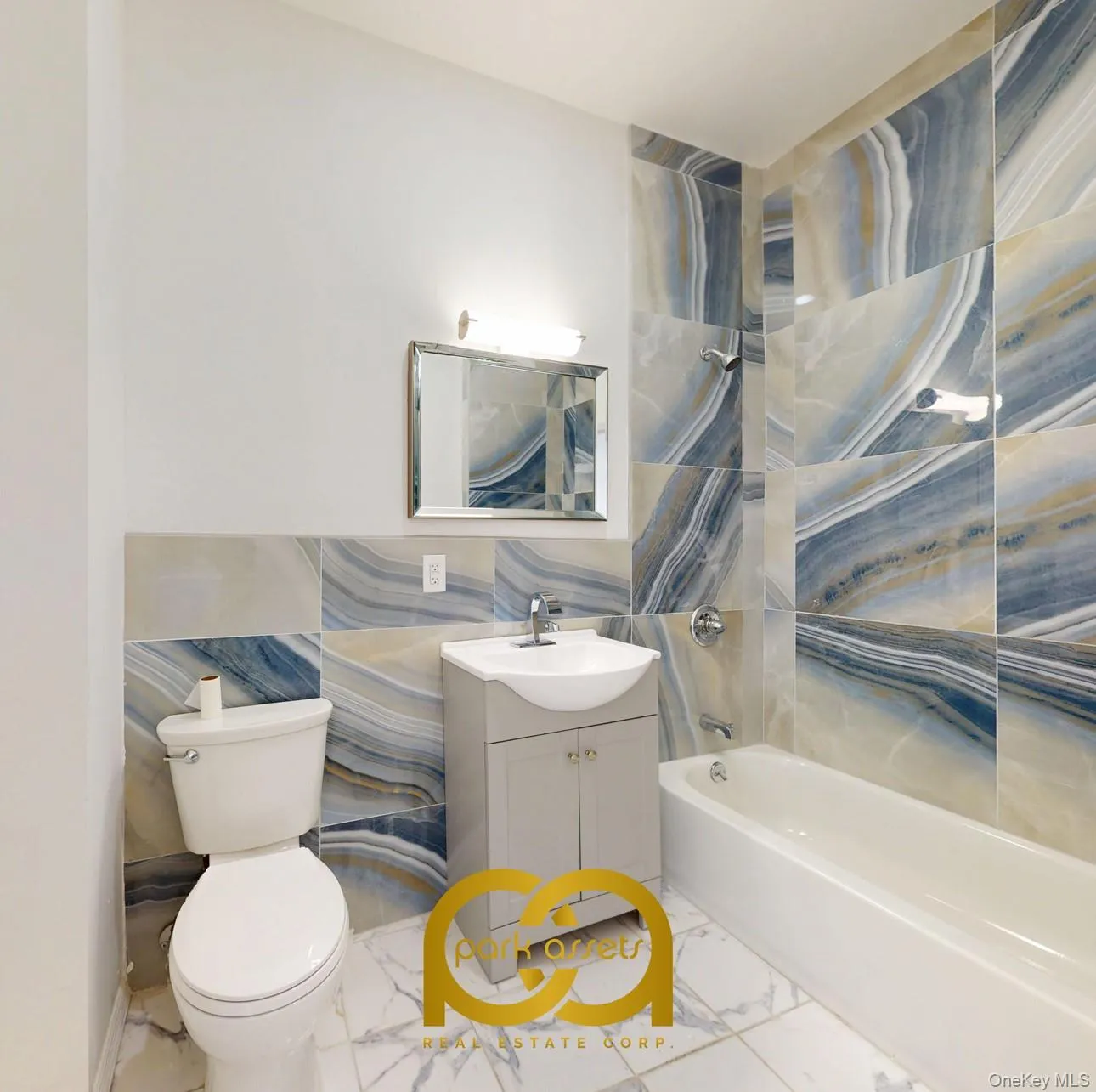 Full bathroom with washtub / shower combination, vanity, light marble finish flooring, and tile walls Full bathroom with washtub / shower combination, vanity, light marble finish flooring, and tile walls