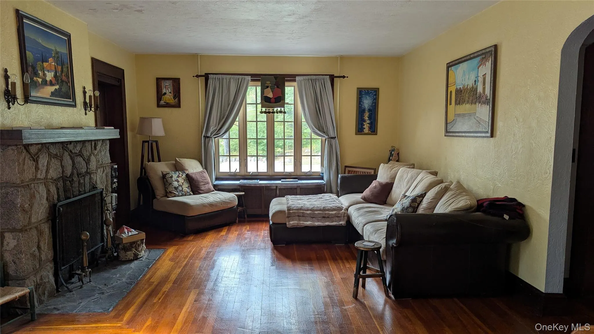 Living area with a textured wall, arched walkways, wood finished floors, a fireplace, and a textured ceiling Living area with a textured wall, arched walkways, wood finished floors, a fireplace, and a textured ceiling