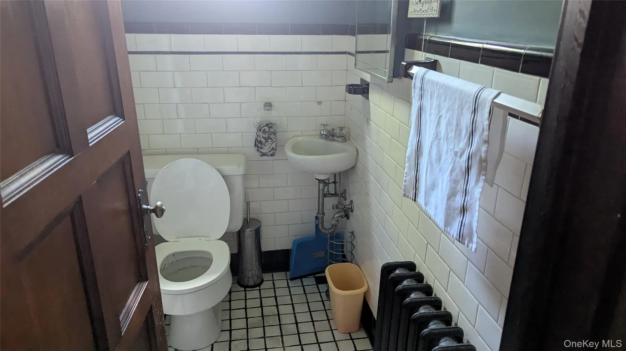 Bathroom with radiator heating unit, tile walls, and light tile patterned floors Bathroom with radiator heating unit, tile walls, and light tile patterned floors