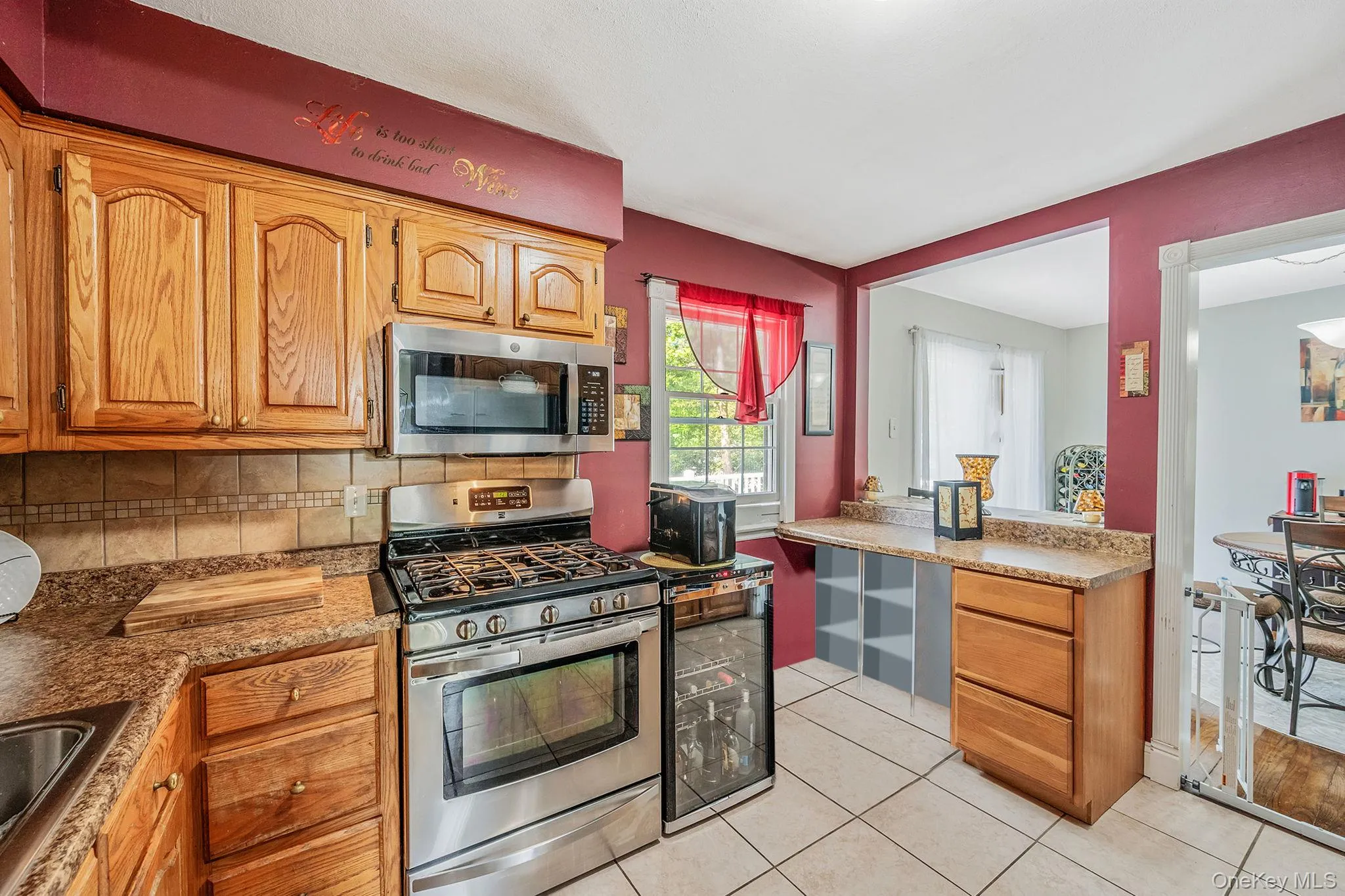 Kitchen with stainless steel appliances, decorative backsplash, light tile patterned floors, brown cabinetry, and light stone countertops Kitchen with stainless steel appliances, decorative backsplash, light tile patterned floors, brown cabinetry, and light stone countertops