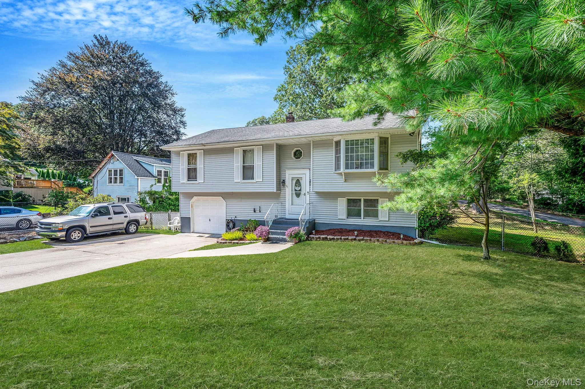 Raised ranch featuring driveway, an attached garage, and a chimney Raised ranch featuring driveway, an attached garage, and a chimney