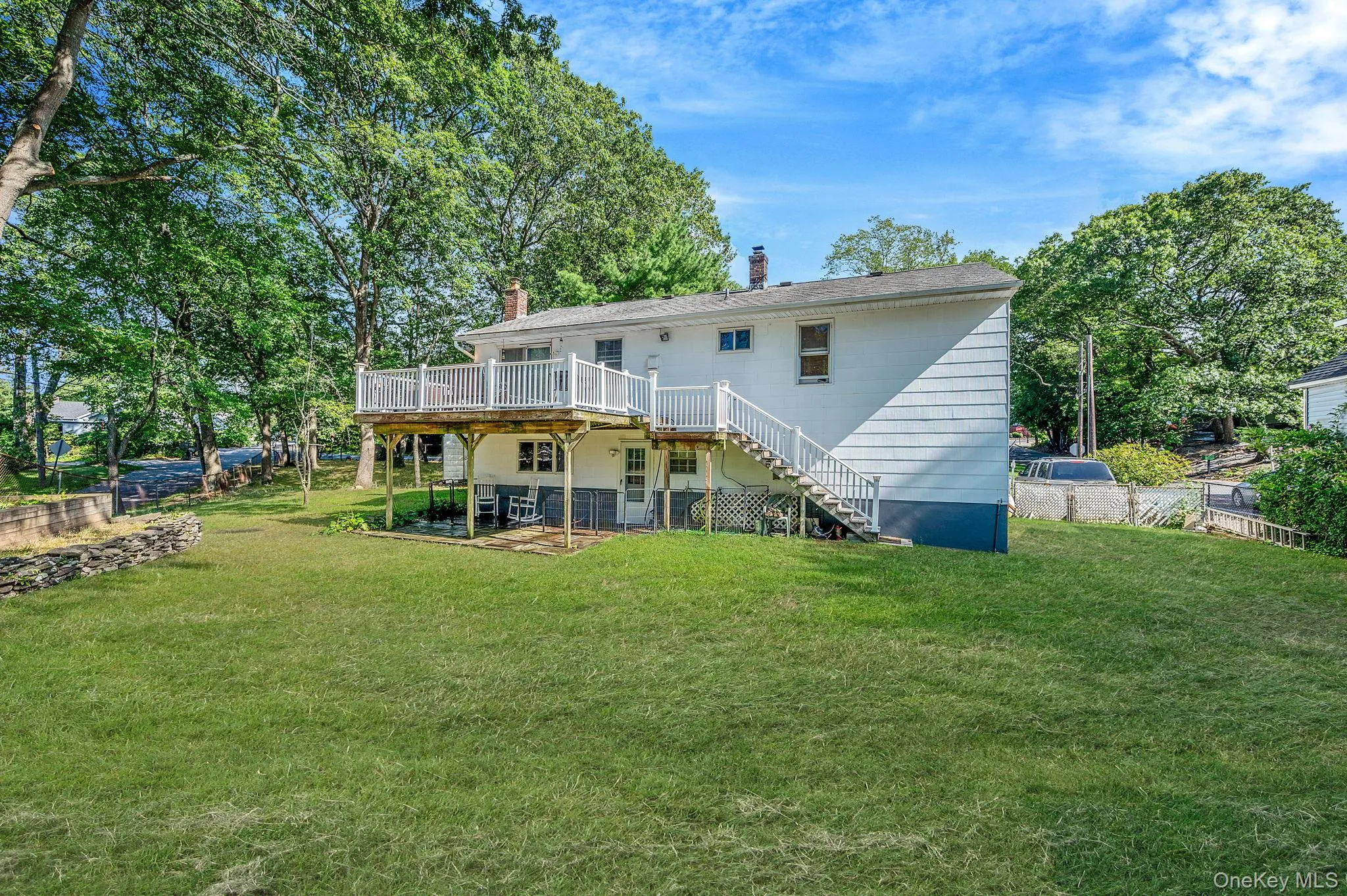 Back of house with a chimney, stairway, a deck, a patio, and a yard Back of house with a chimney, stairway, a deck, a patio, and a yard