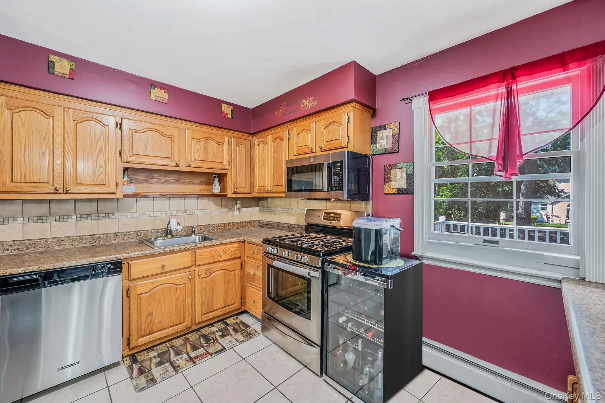 Kitchen featuring decorative backsplash, appliances with stainless steel finishes, a baseboard radiator, and light tile patterned floors Kitchen featuring decorative backsplash, appliances with stainless steel finishes, a baseboard radiator, and light tile patterned floors