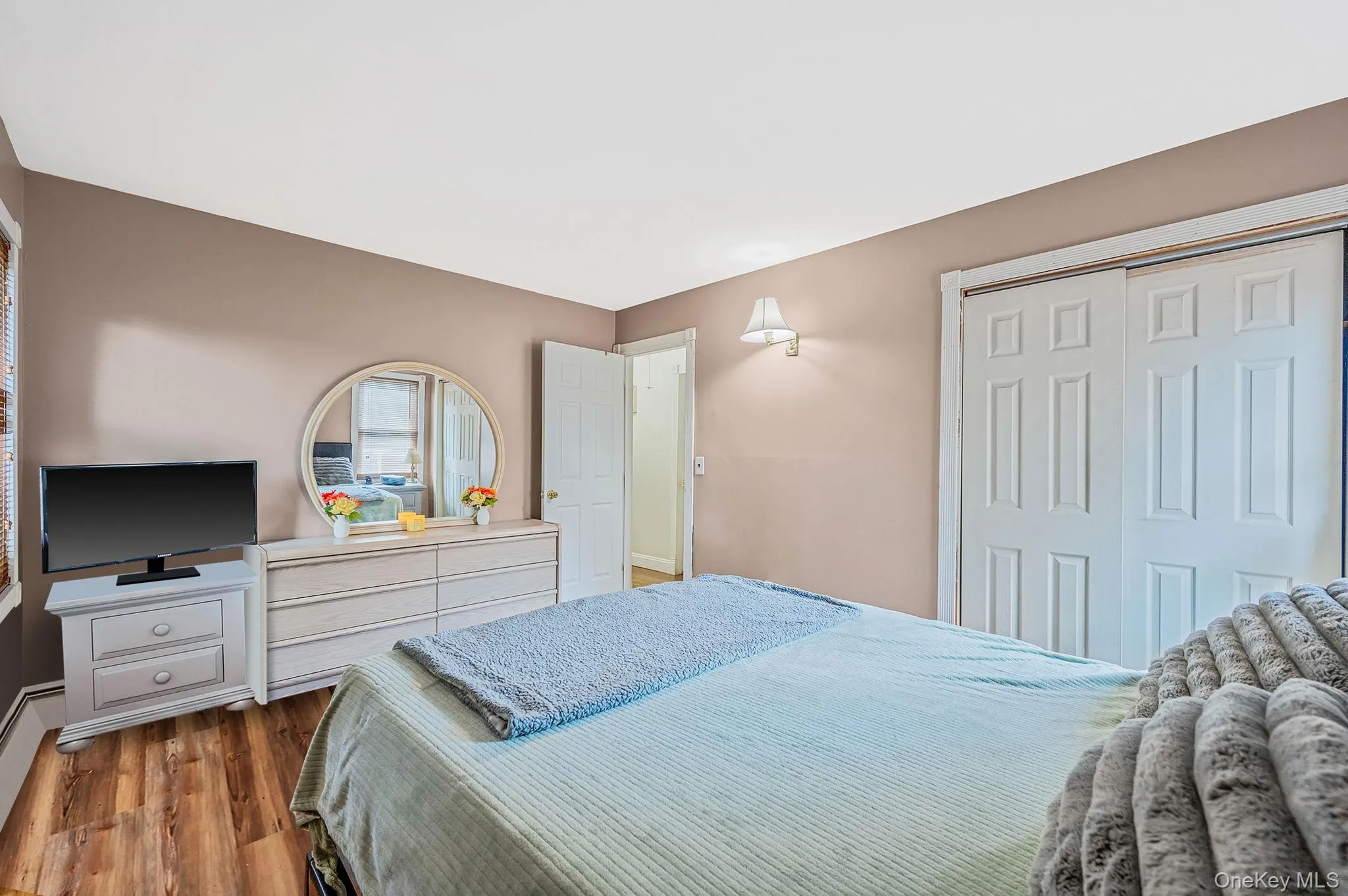 Bedroom featuring wood finished floors, a closet, and a baseboard radiator Bedroom featuring wood finished floors, a closet, and a baseboard radiator