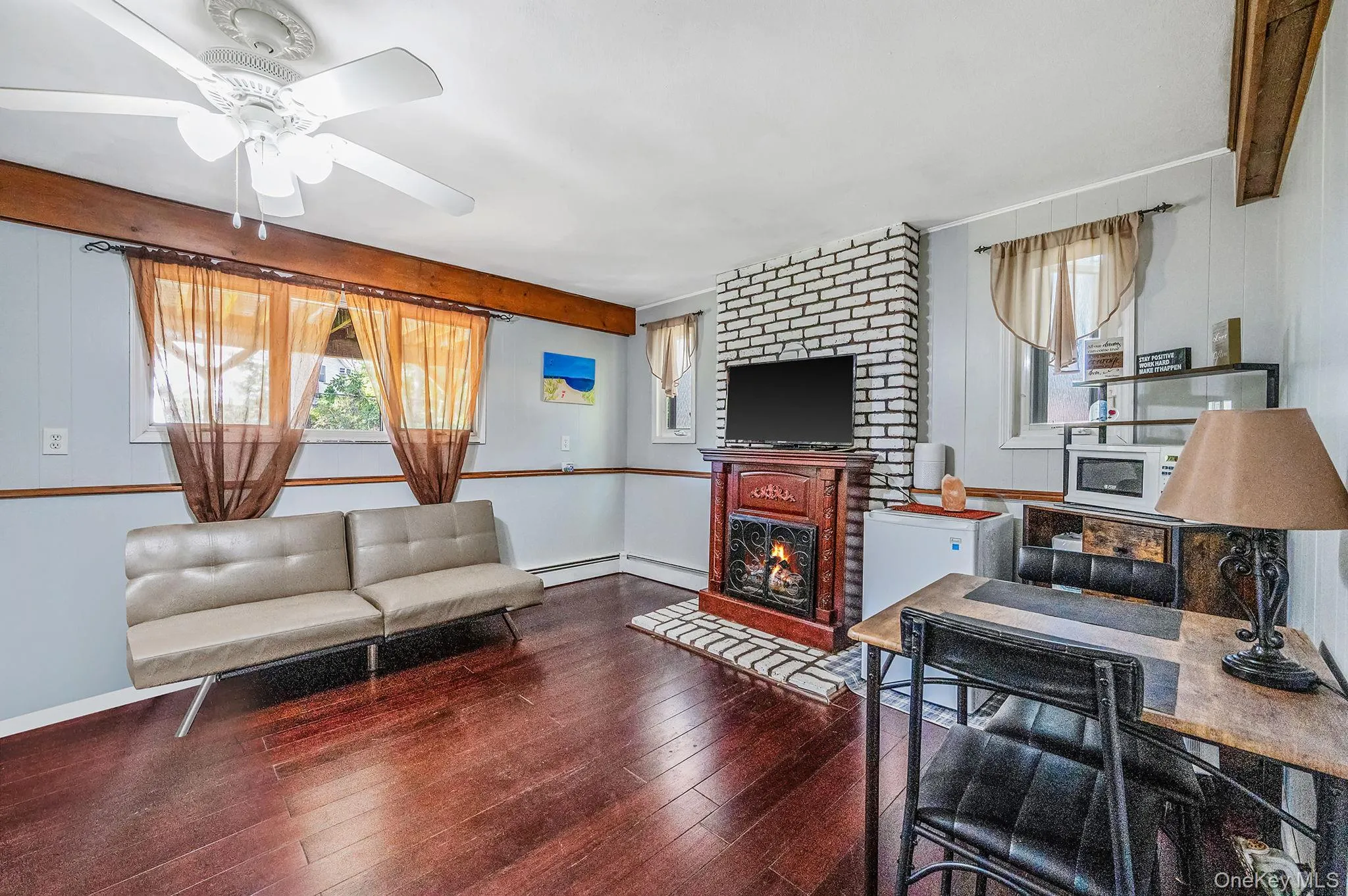 Living area with wood-type flooring, healthy amount of natural light, a fireplace, and ceiling fan Living area with wood-type flooring, healthy amount of natural light, a fireplace, and ceiling fan