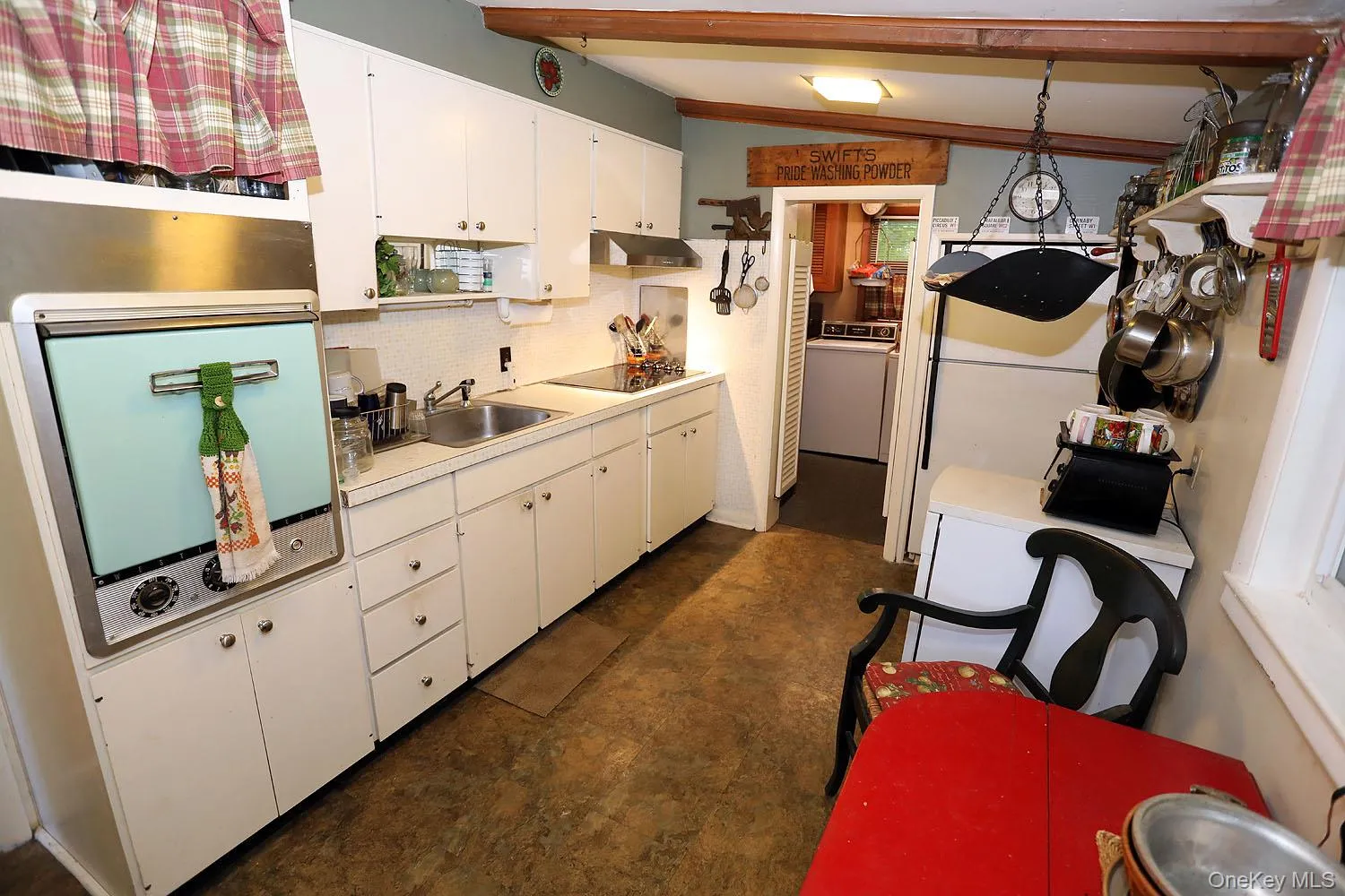 Kitchen featuring decorative backsplash, white cabinets, light countertops, under cabinet range hood, and washer / clothes dryer Kitchen featuring decorative backsplash, white cabinets, light countertops, under cabinet range hood, and washer / clothes dryer
