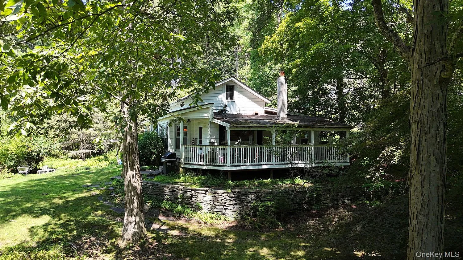 Rear view of house with a lawn, covered porch, and a view of trees Rear view of house with a lawn, covered porch, and a view of trees