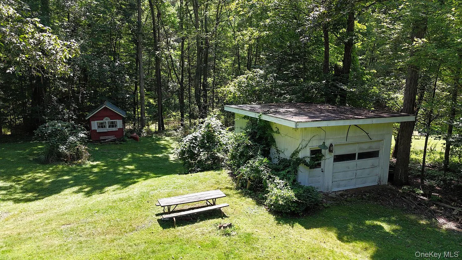 View of green lawn featuring a garage and outbuilding View of green lawn featuring a garage and outbuilding