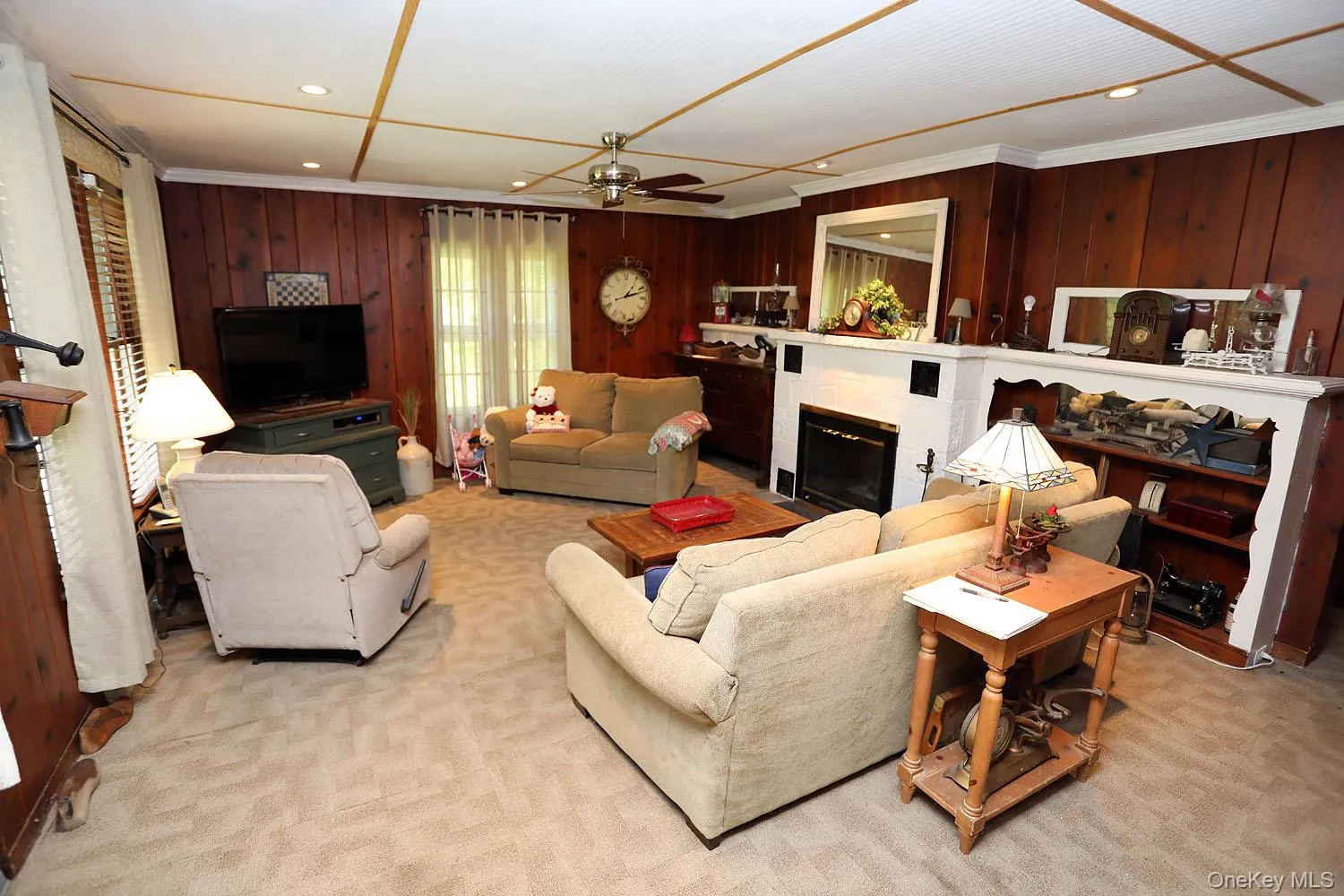 Living area with a glass covered fireplace, light carpet, recessed lighting, a ceiling fan, and wooden walls Living area with a glass covered fireplace, light carpet, recessed lighting, a ceiling fan, and wooden walls