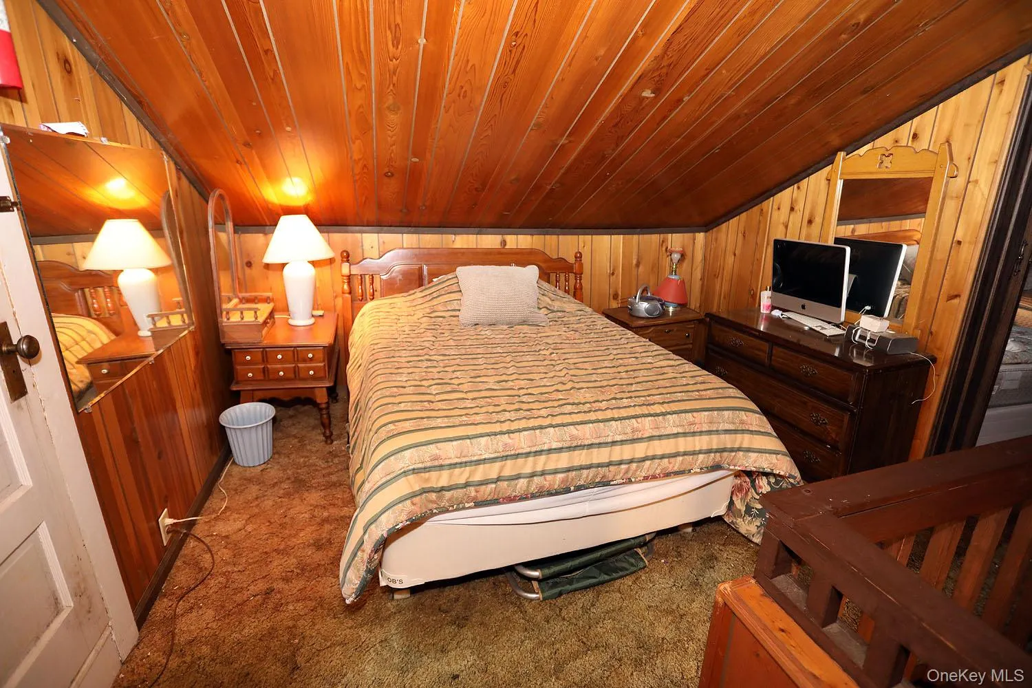 Bedroom with wooden walls, wood ceiling, and dark colored carpet Bedroom with wooden walls, wood ceiling, and dark colored carpet
