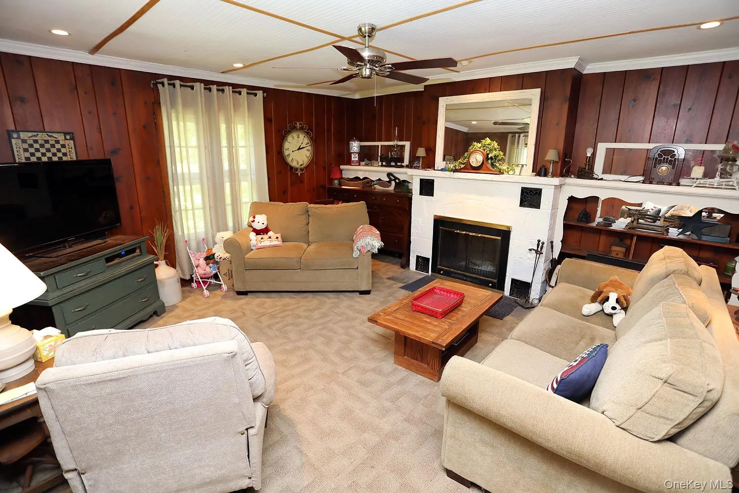 Carpeted living room with ornamental molding, wooden walls, recessed lighting, a glass covered fireplace, and a ceiling fan Carpeted living room with ornamental molding, wooden walls, recessed lighting, a glass covered fireplace, and a ceiling fan