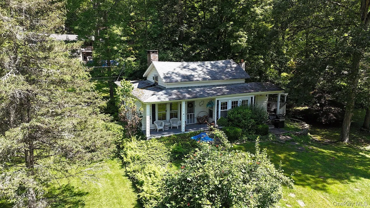 View of front of house featuring a chimney, covered porch, a front yard, and a view of trees View of front of house featuring a chimney, covered porch, a front yard, and a view of trees