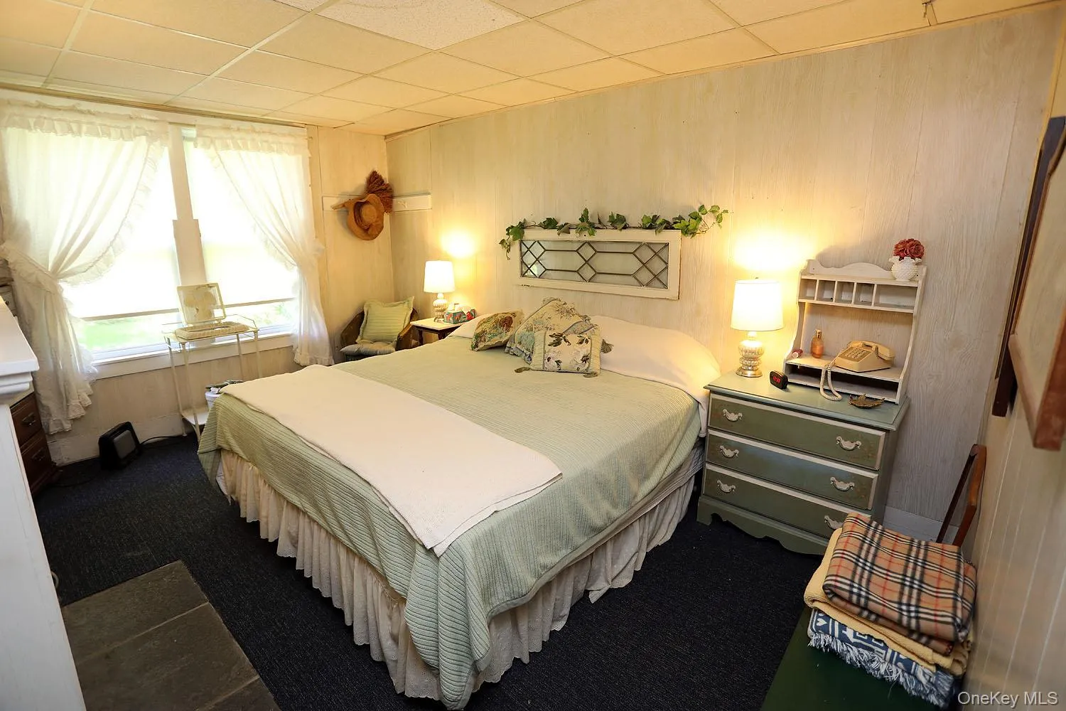 Bedroom featuring carpet floors, wooden walls, and a paneled ceiling Bedroom featuring carpet floors, wooden walls, and a paneled ceiling
