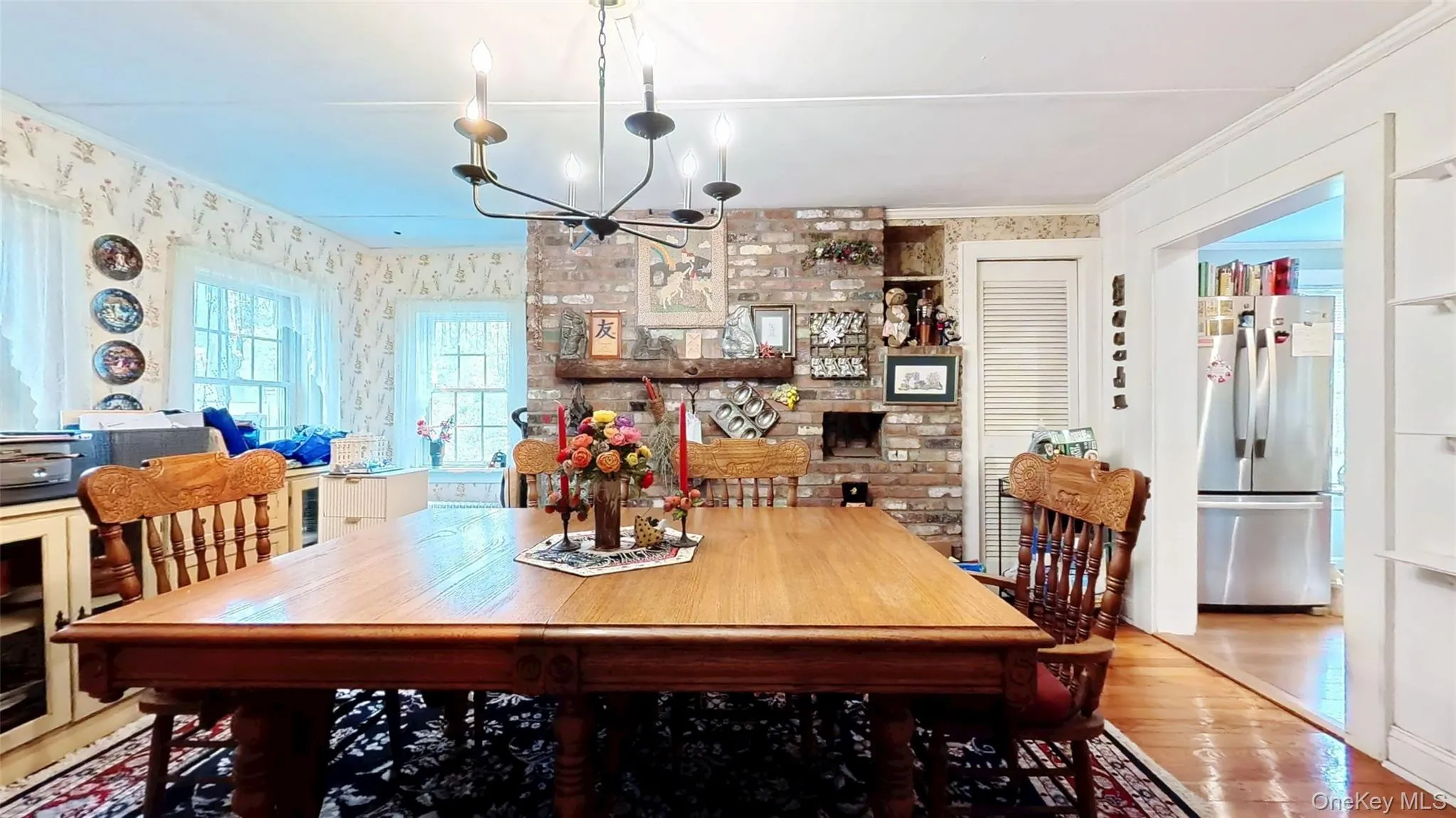 Dining room with a chandelier, wood floors, ornamental molding, and wallpapered accent wall Dining room with a chandelier, wood floors, ornamental molding, and wallpapered accent wall