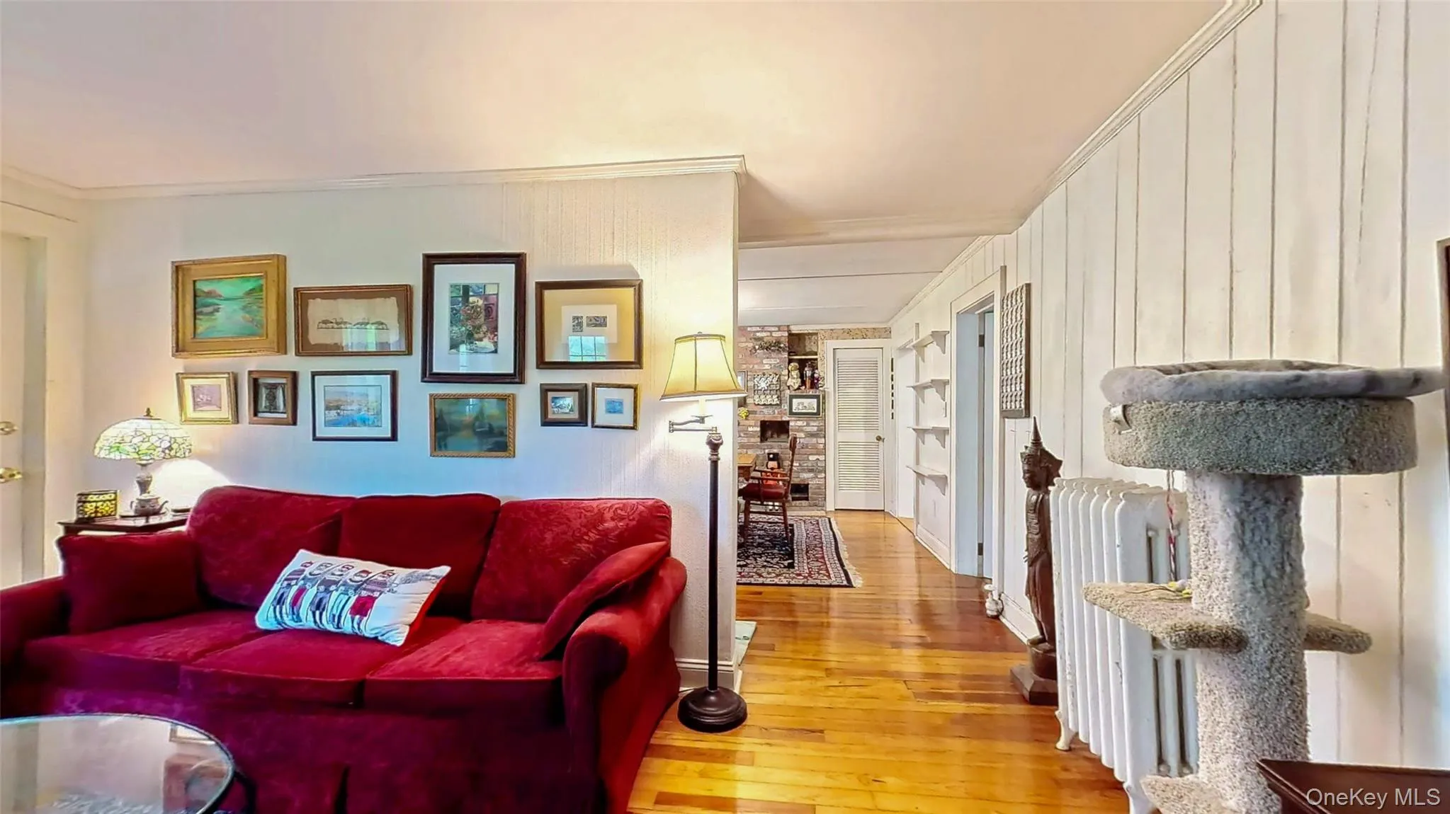 Living room featuring light wood flooring, ornamental molding, radiator, and built in shelves Living room featuring light wood flooring, ornamental molding, radiator, and built in shelves