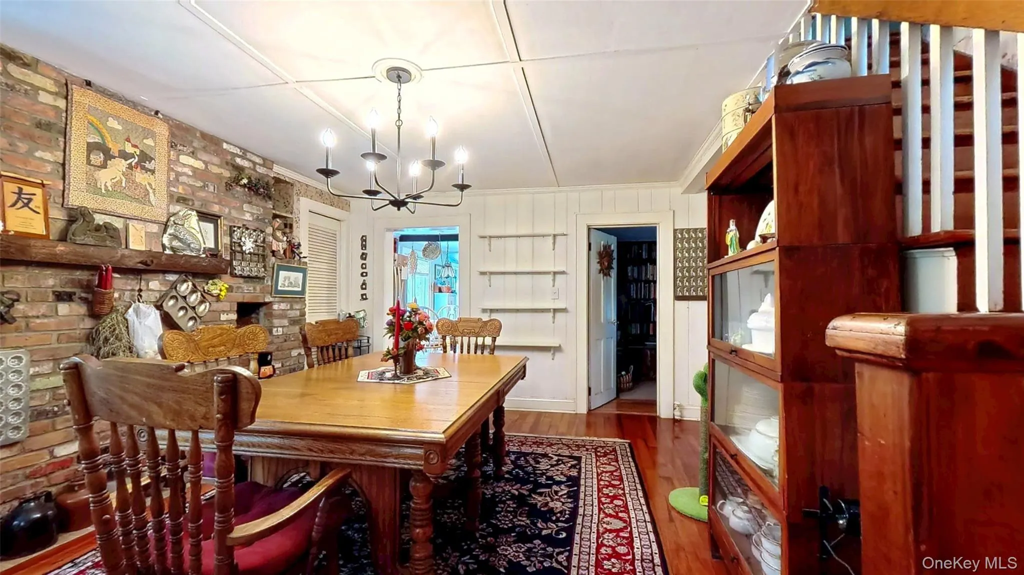 Dining room featuring dark wood flooring, a chandelier, brick wall over Dutch oven, and crown molding Dining room featuring dark wood flooring, a chandelier, brick wall over Dutch oven, and crown molding