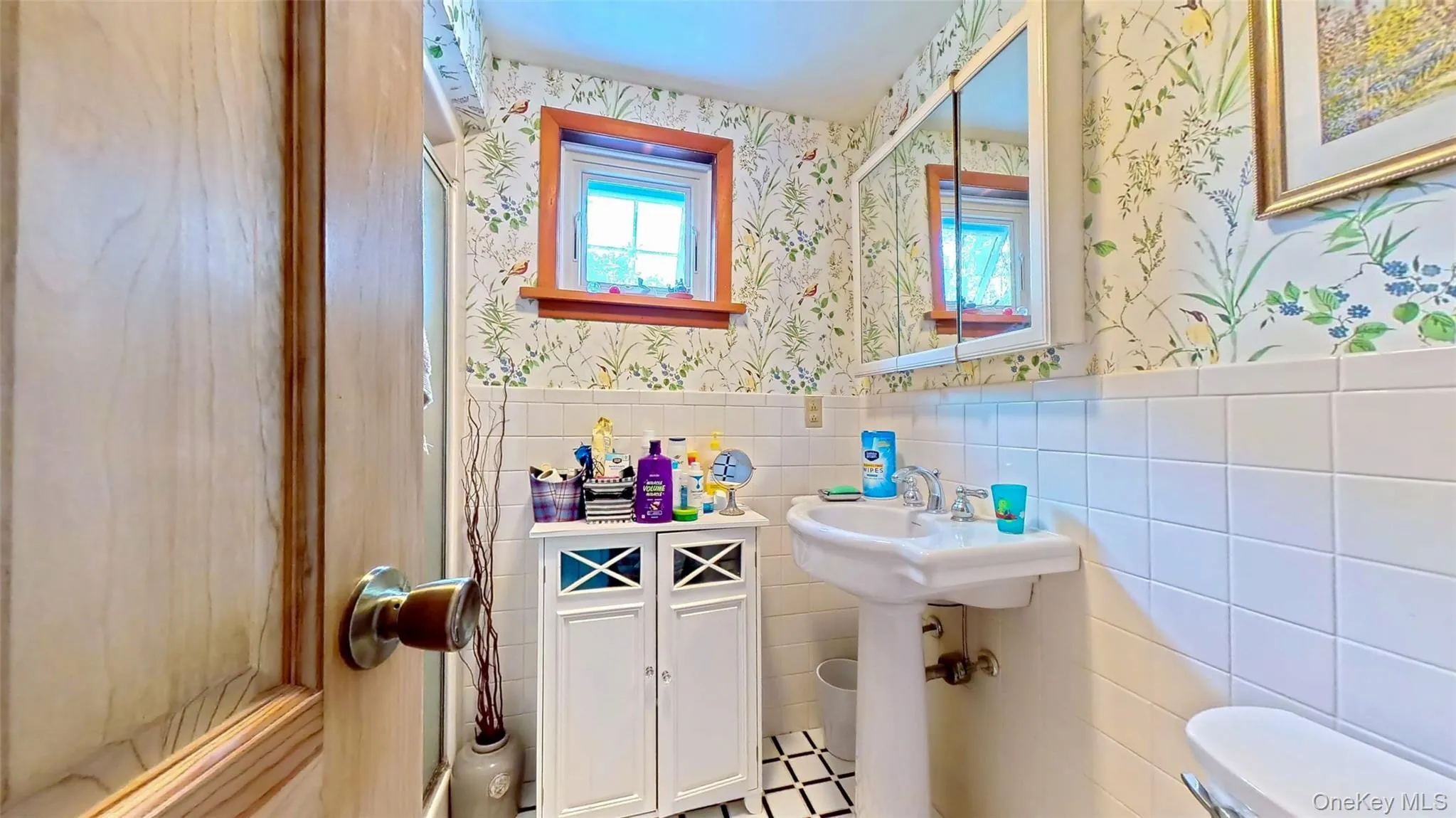 Full updated bathroom featuring tile walls, wainscoting, wallpapered walls and window for natural light Full updated bathroom featuring tile walls, wainscoting, wallpapered walls and window for natural light