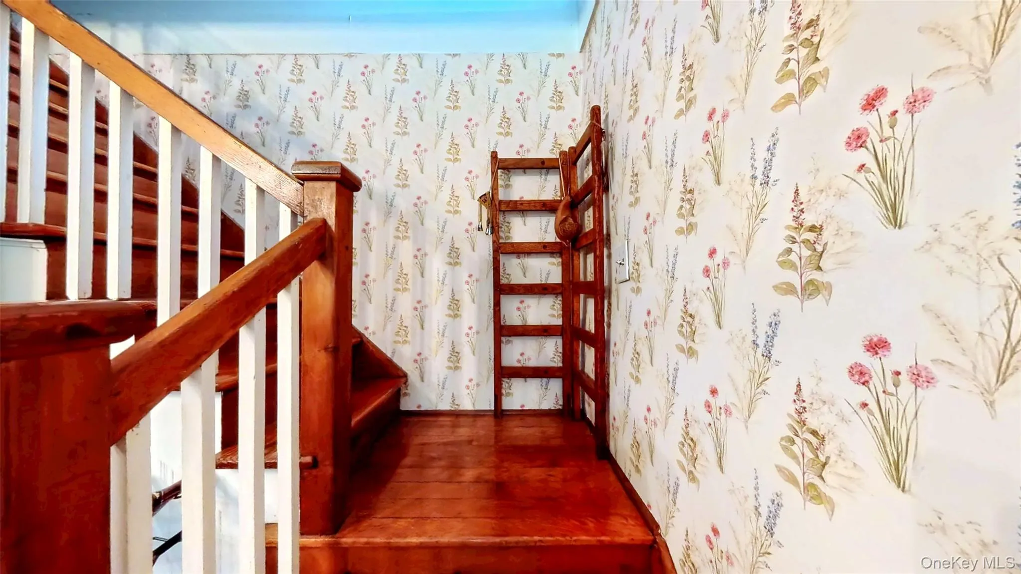Stairway to second story featuring wallpapered walls and wood floors Stairway to second story featuring wallpapered walls and wood floors