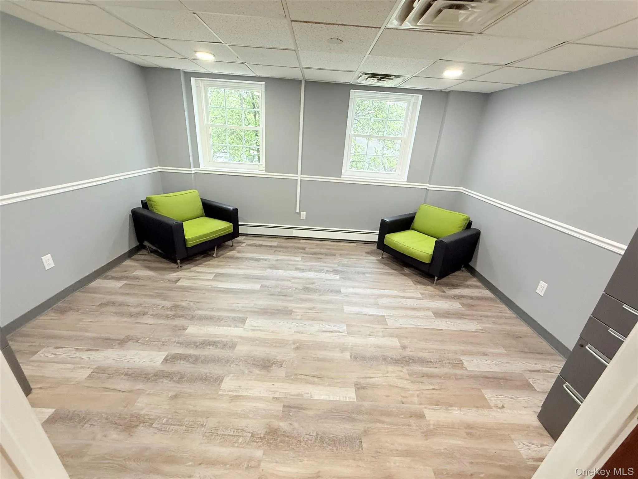 Sitting room featuring a drop ceiling, light wood-type flooring, and a baseboard heating unit Sitting room featuring a drop ceiling, light wood-type flooring, and a baseboard heating unit