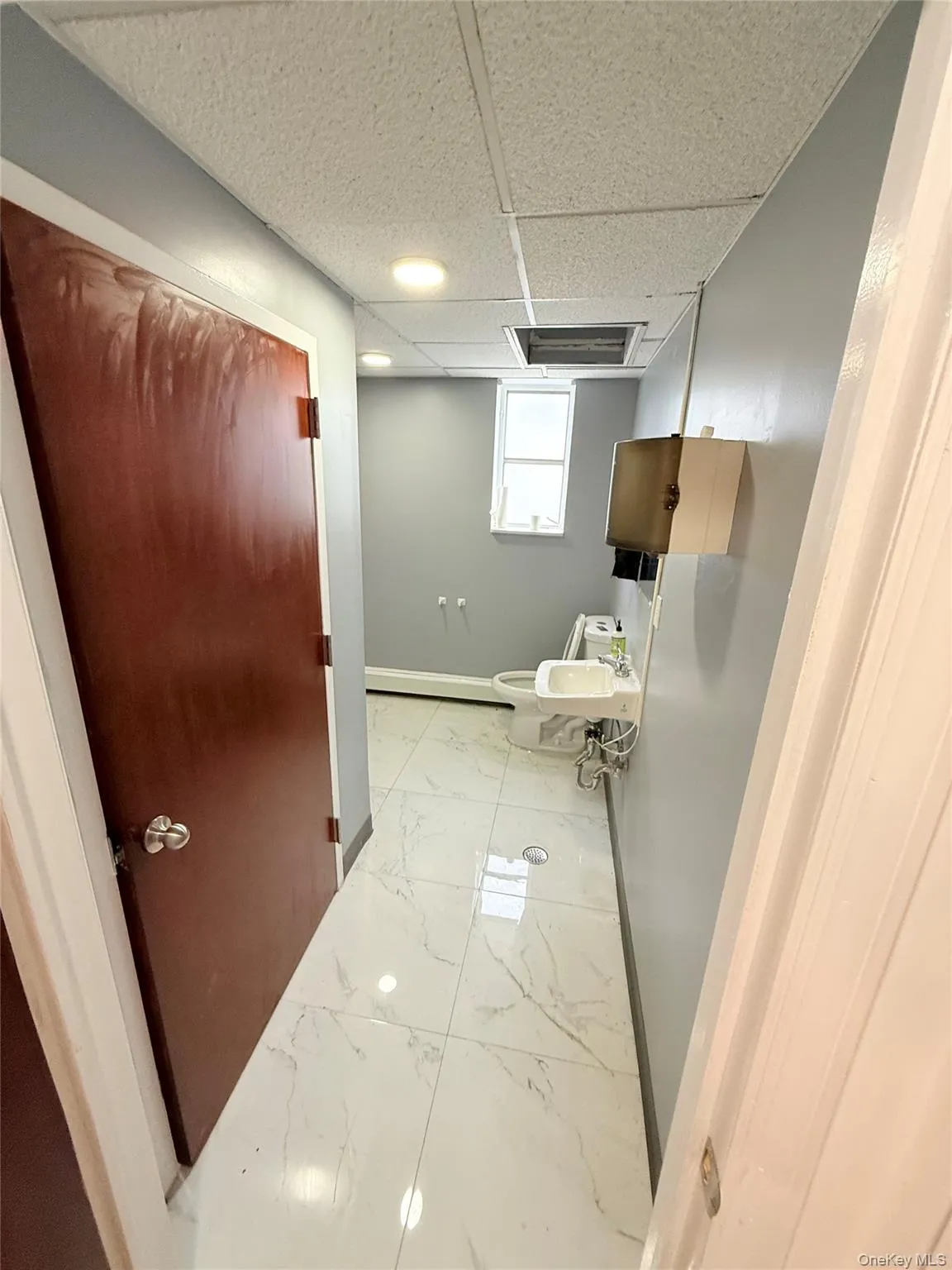 Half bath featuring a paneled ceiling and light marble finish flooring Half bath featuring a paneled ceiling and light marble finish flooring
