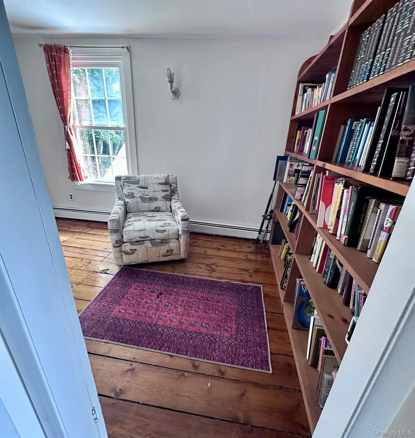 Living area with dark wood-type flooring and baseboard heating Living area with dark wood-type flooring and baseboard heating
