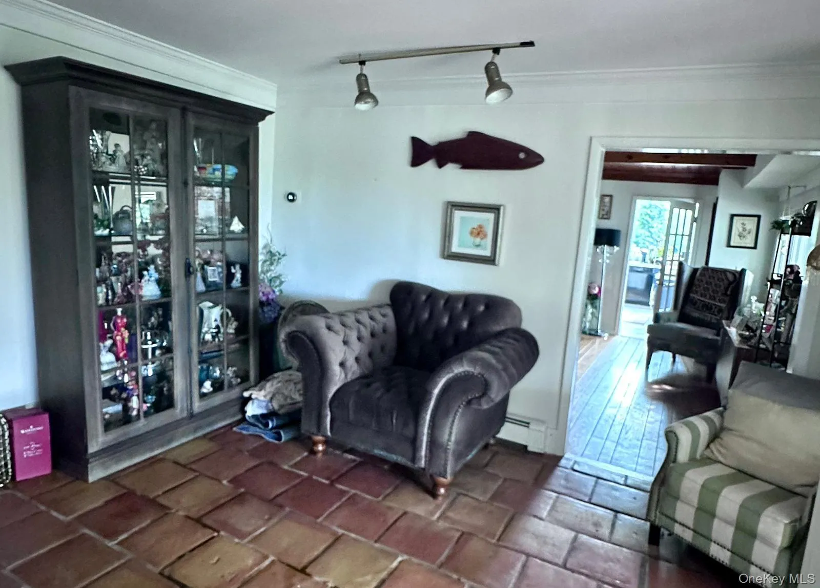 Living area with rail lighting, a baseboard heating unit, crown molding, and stone tile floors Living area with rail lighting, a baseboard heating unit, crown molding, and stone tile floors