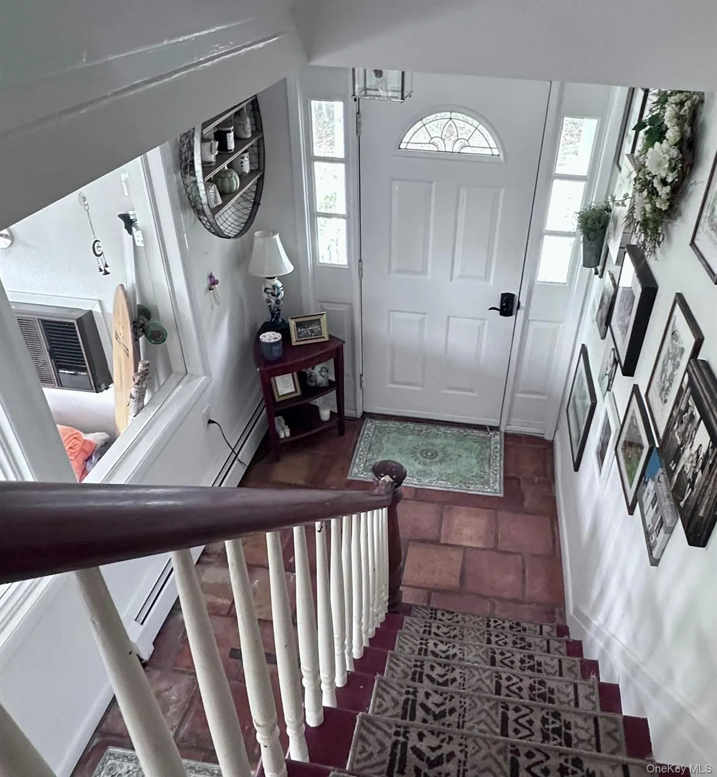 Entrance foyer with stairway, stone tile floors, and a baseboard radiator Entrance foyer with stairway, stone tile floors, and a baseboard radiator