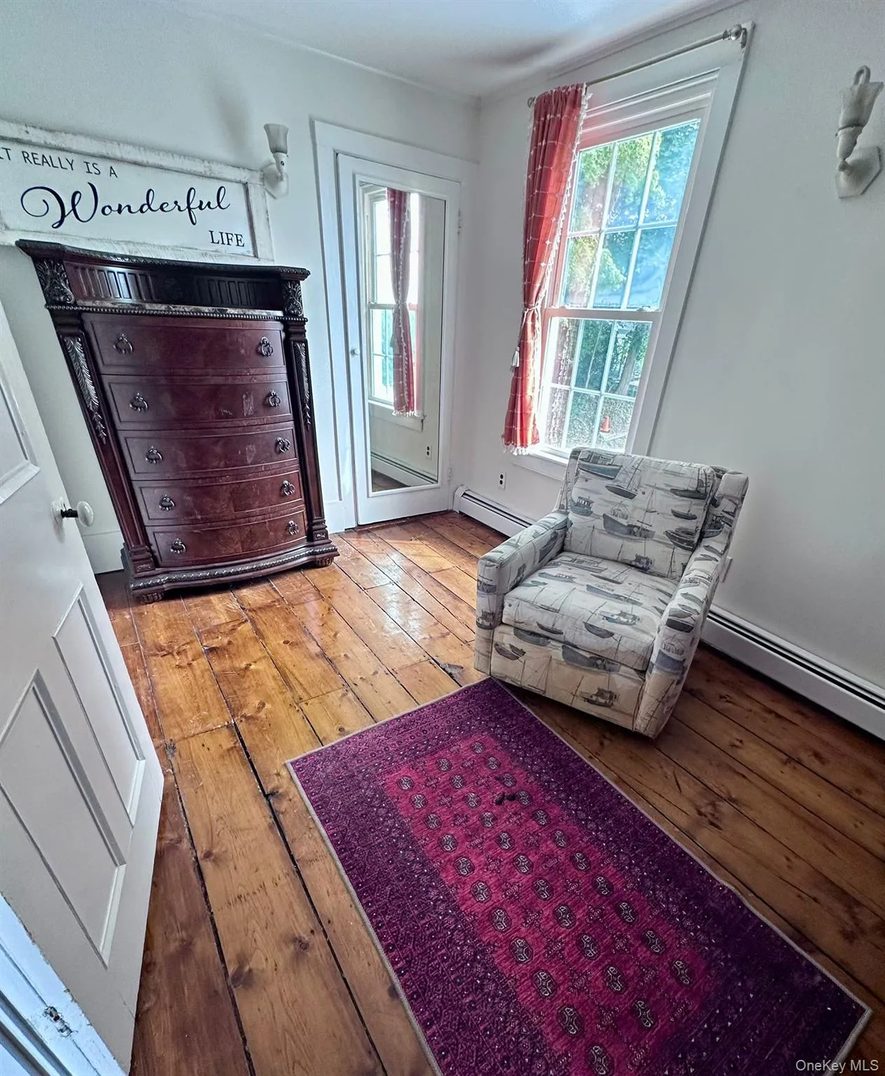 Living area with a baseboard heating unit, healthy amount of natural light, and light wood-style flooring Living area with a baseboard heating unit, healthy amount of natural light, and light wood-style flooring