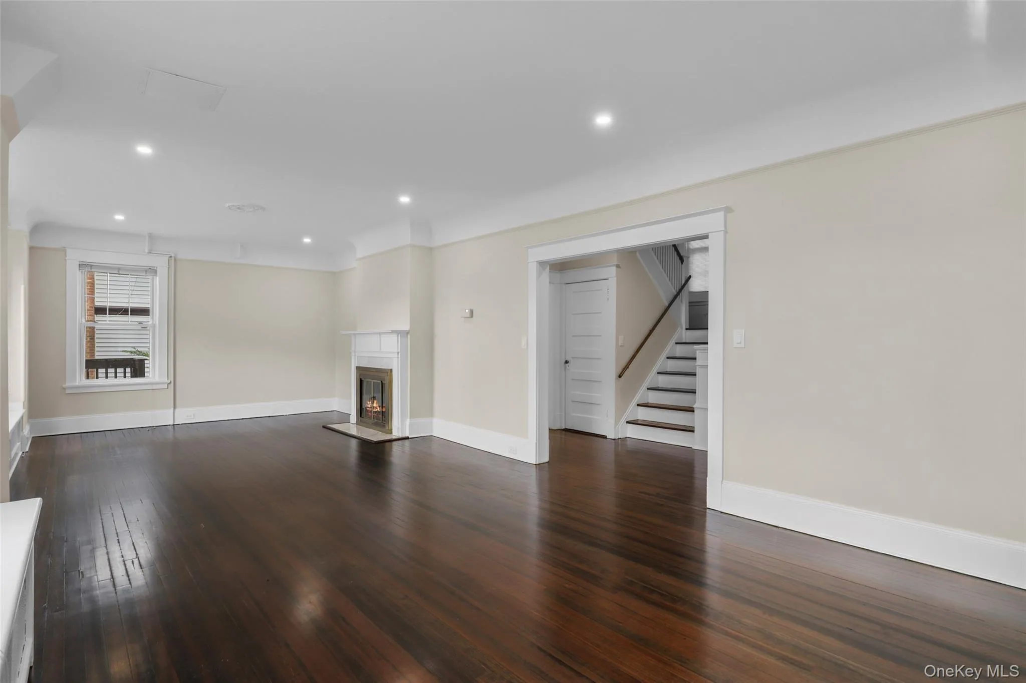 Unfurnished living room featuring dark wood finished floors, stairs, recessed lighting, and a glass covered fireplace Unfurnished living room featuring dark wood finished floors, stairs, recessed lighting, and a glass covered fireplace