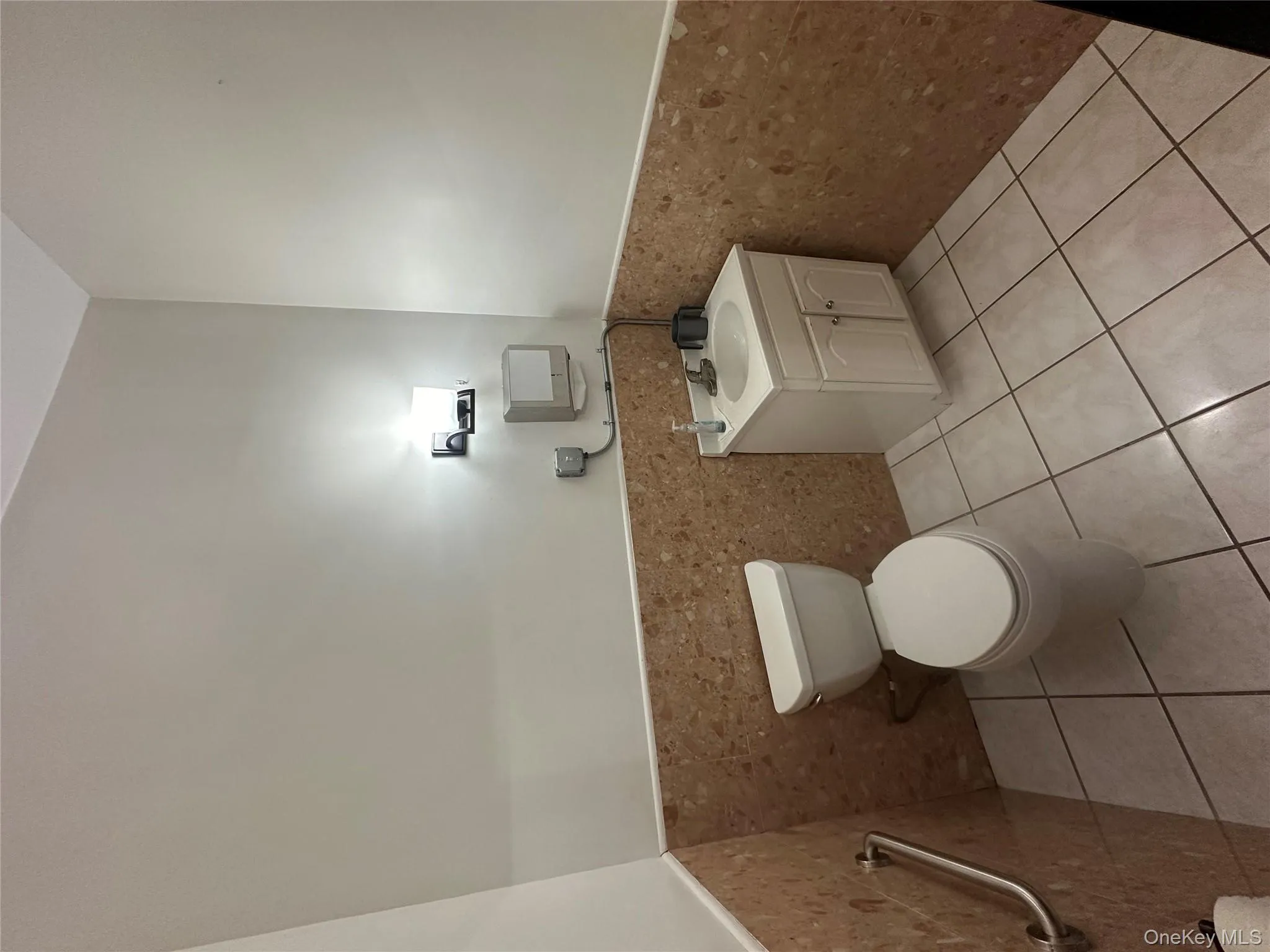 Half bathroom featuring wainscoting, tile walls, light tile patterned flooring, and vanity Half bathroom featuring wainscoting, tile walls, light tile patterned flooring, and vanity