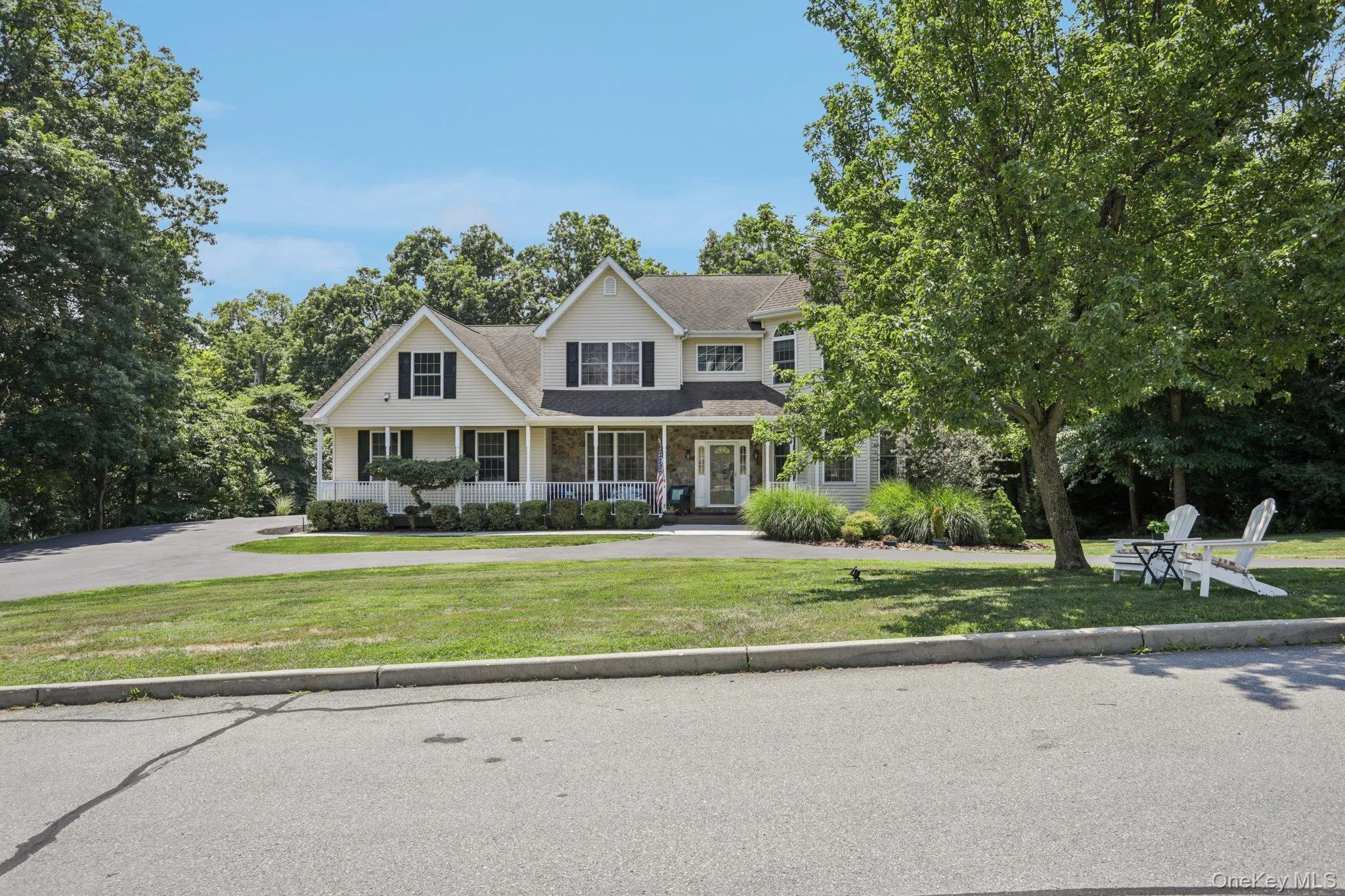 View of front of home with covered porch, a front lawn, stone siding, and a shingled roof View of front of home with covered porch, a front lawn, stone siding, and a shingled roof