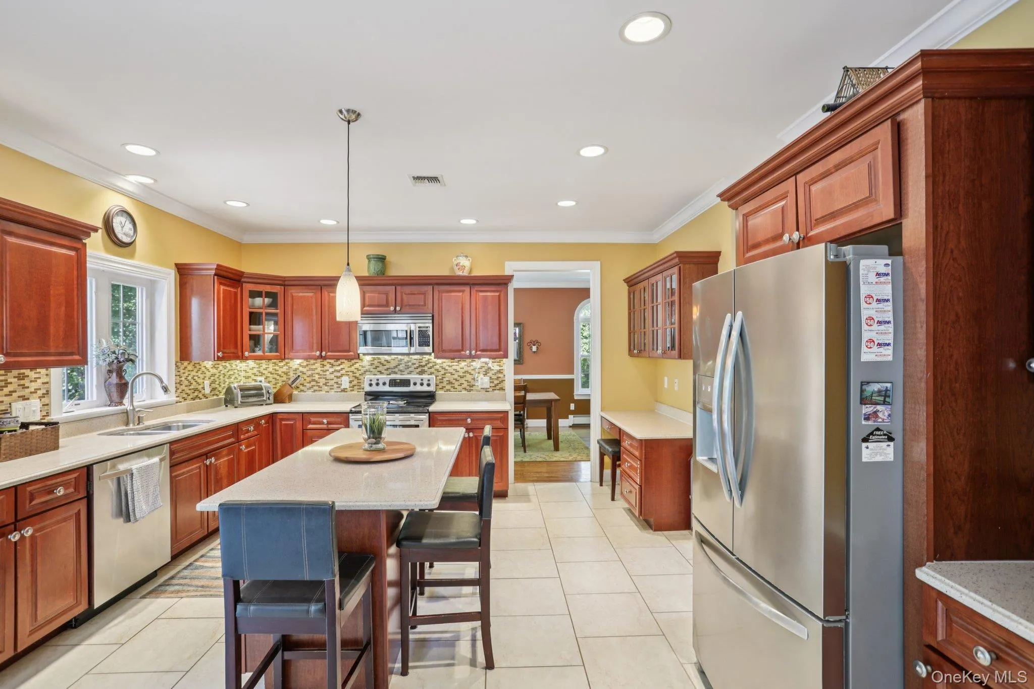 Kitchen with glass insert cabinets, stainless steel appliances, a kitchen breakfast bar, ornamental molding, and healthy amount of natural light Kitchen with glass insert cabinets, stainless steel appliances, a kitchen breakfast bar, ornamental molding, and healthy amount of natural light