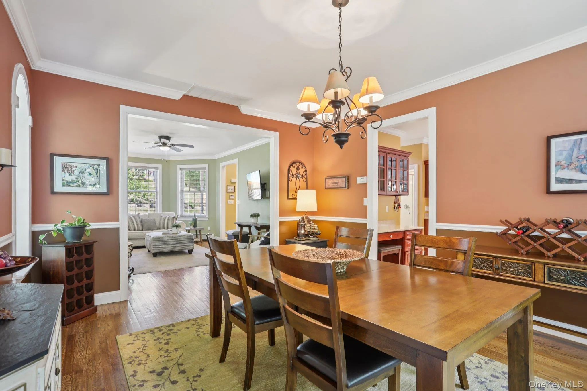 Dining room with dark wood-type flooring, ornamental molding, a ceiling fan, and a chandelier Dining room with dark wood-type flooring, ornamental molding, a ceiling fan, and a chandelier
